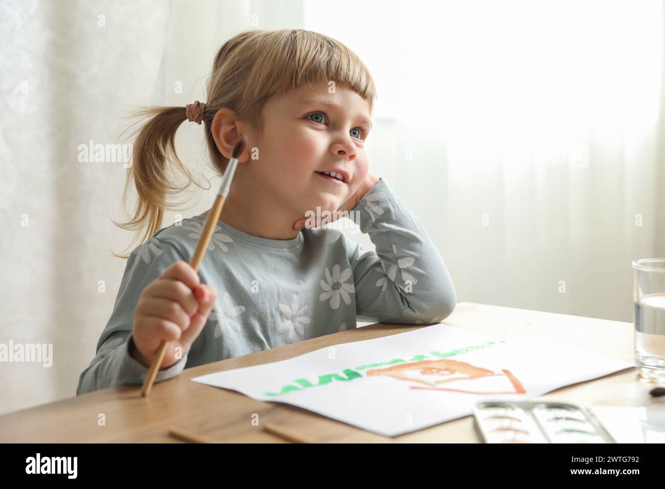 Cute little girl drawing at wooden table indoors. Child`s art Stock Photo